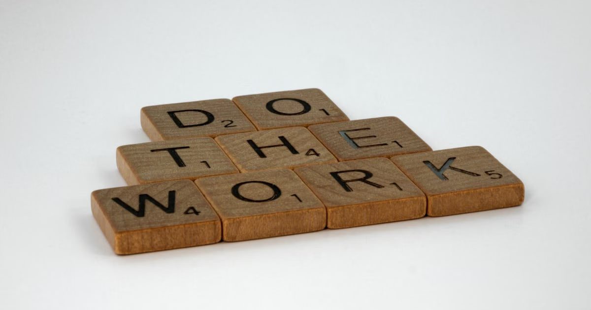 Motivational message spelled out with scrabble tiles on white background.