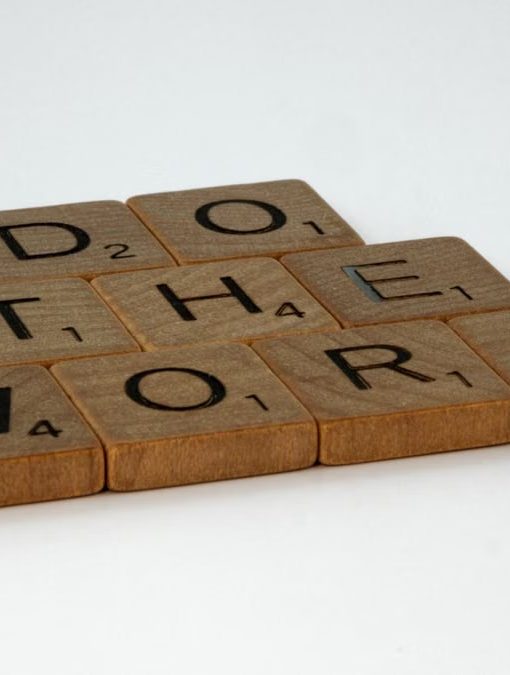 Motivational message spelled out with scrabble tiles on white background.