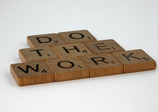 Motivational message spelled out with scrabble tiles on white background.